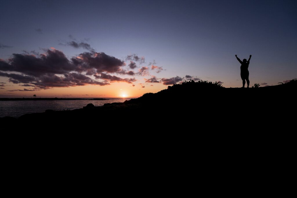 pexels photo 136415 136415 Silhouette of a person celebrating at a stunning sunset by the ocean.
